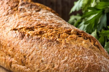 Arka planda taze pişmiş ev yapımı ekmek ve maydanoz demeti yakın plan.