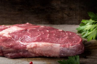 Ahşap arka planda maydanozlu çiğ kaburga bifteği.