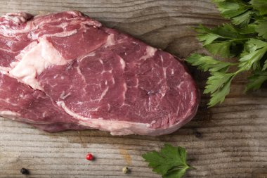 Ahşap arka planda maydanozlu çiğ kaburga bifteği.