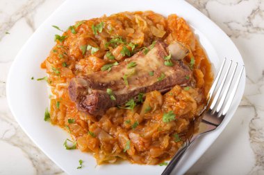 Kabak füme domuz kaburgası ve çatallı beyaz tabakta servis edilen yeşil maydanozla pişirilir.