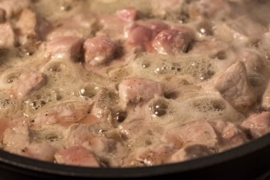 Küçük domuz parçalarını tavada kızartıyorsun.