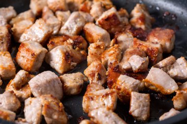 Tavadaki küçük kızarmış domuz parçalarını yakın.