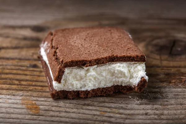 Tahta arka planda süt ve yoğurt kreması dolu kırık bir pastanın kapağını kapat.