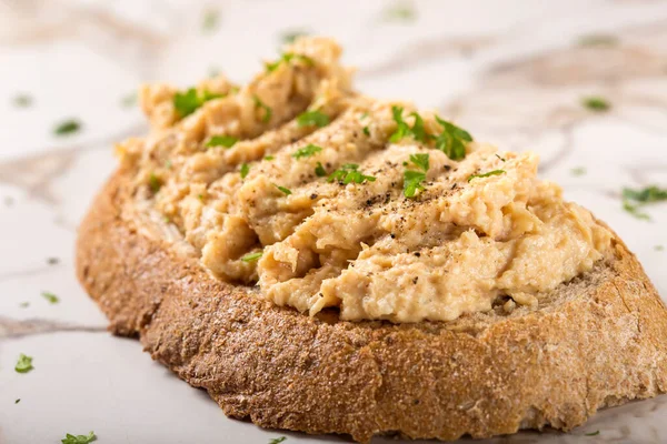 Kremalı ekmek dilimi. Püre tavuk göğsünden yapılmış. Şifalı otlar ve masada karabiber var.