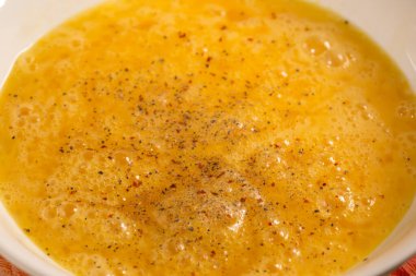 Beyaz kâsede çırpılmış yumurta, biber, tuz ve kırmızı biber.