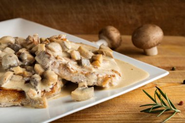 Ekşi krema soslu domuz filetosu ve ahşap zemin üzerinde mantar.