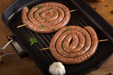 Izgara tavasını lezzetli sosisler ve otlarla kapat.