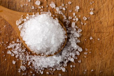 Ahşap arka planda tahta kaşıkta deniz tuzu