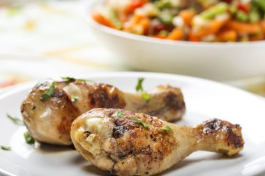 İki ızgara tavuk budu, palette maydanoz ve arka planda salata.