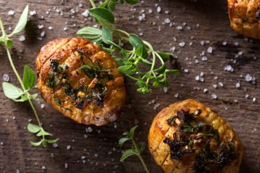 Farklı otlarla pişirilmiş akordeon fırında patates ve ahşap kırsal arka planda deniz tuzu.