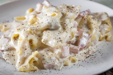 Tortellini ve füme jambon, mantar ve ekşi krema soslu ravioli.