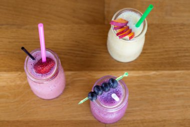 Çilek, kızılcık ve yoğurtla harmanlanmış mango içeren taze organik içerikli üç meyveli milkshake.