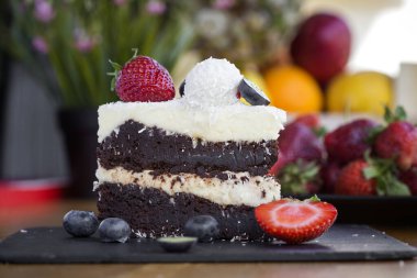 Beyaz ve siyah çikolatadan yapılmış lezzetli çikolatalı pasta, meyveler ve hindistan cevizi.