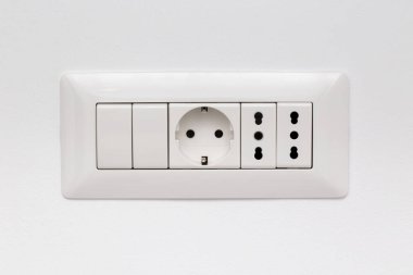 Modüler soket üç güç prizi ve beyaz duvardaki iki anahtar tarafından oluşturuldu.