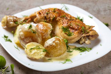 Bir kızarmış tavuk budu, yeni patates ve beyaz tabakta ekşi krema sosu.