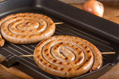 Izgara tavasında iki kızarmış domuz sosisi. Yakın çekim.