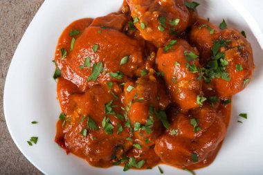 Domates soslu köfte ve taze doğranmış maydanoz tabakta.