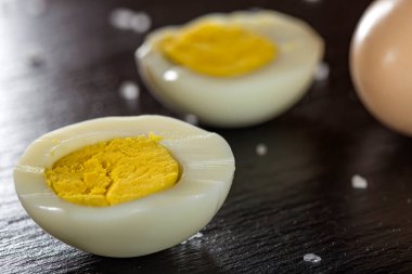 Koyu bir levhada deniz tuzu ile kaynamış yumurta dilimleri. Yakın görüş.