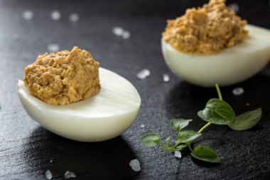 Doldurulmuş yumurta ve tavuk eti. Koyu bir levhada ezme. Yakın çekim.