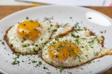 Beyaz tabakta iki kızarmış yumurta, tuzlu, karabiberli ve yeşil karabiberli