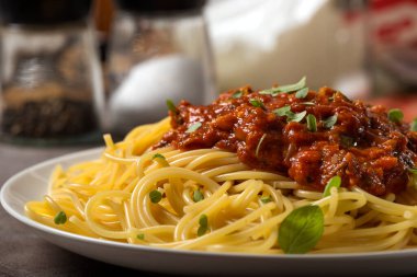 Akdeniz ton balığı soslu spagetti, taze kekik yaprakları ve beyaz tabakta ekstra saf İtalyan zeytinyağı.