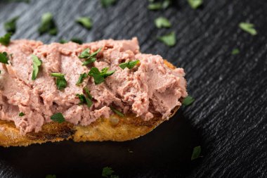 Kara tahtada doğranmış maydanozlu ciğer sosisli sandviç.