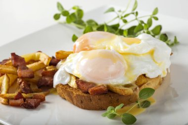 İki haşlanmış yumurta, patates kızartması ve pastırmalı tost.