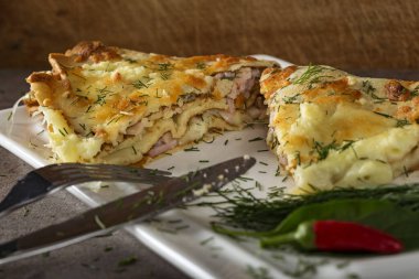 Beyaz tabakta göğüs, krema ve jambonla doldurulmuş fırında krep. Yakın çekim.