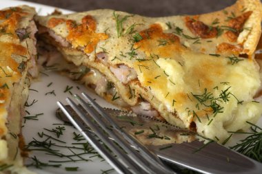 Beyaz tabakta göğüs, krema ve jambonla doldurulmuş fırında krep. Yakın çekim.