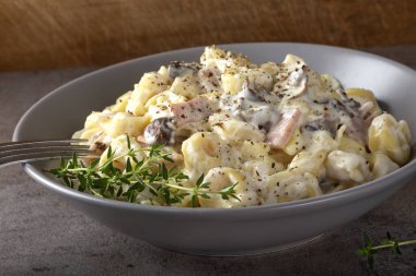 Mantarlı Ravioli ve krema ve peynir soslu jambon. İtalyan mutfağı.