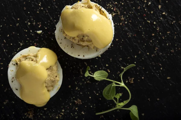 Doldurulmuş yumurta ve mayonez, arka planda koyu renkli otlar.