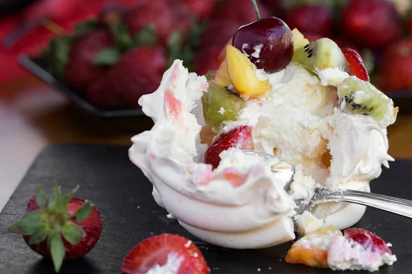 Az yağlı kremalı Anna Pavlova kreması ve kaşıklı taze çilek yemek.