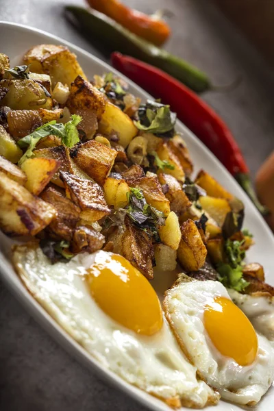 Yumurta ve patates kızartması, küçük parça domuz eti, soğan ve sarımsak tabakta - yakın görüş