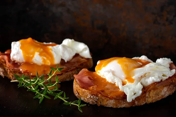 Dar bir tabakta taze yeşil kekik otlarıyla ev yapımı Benedict yumurtaları.