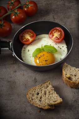 Küçük tavada bir yumurta, kiraz domatesli ve ekmekli. 