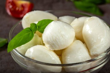 Mozzarella peynirli toplar, vişneli domates ve fesleğenli cam kase. Yakın görüş.