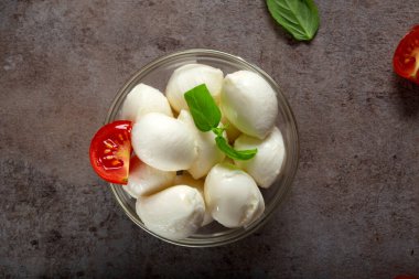 Mozzarella peynirli toplar, kiraz domatesli ve fesleğenli cam kase.