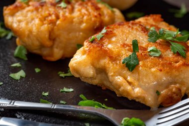 Koyu yeşil maydanozlu iki parça Cordon Bleu. Yakın çekim.