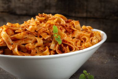 Tagliatelle makarnası, ton balığı sosu ve beyaz kasede otlar. 