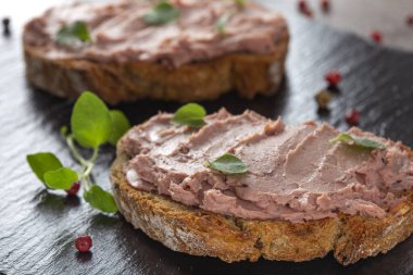 Açık sandviçler, domuz eti ve hindi ciğerinden yapılmış koyu bir levhada tatlı kızılcık reçeli. 