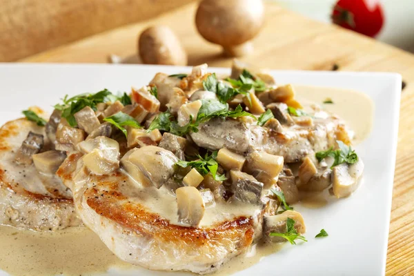 Krema ve mantardan yapılmış soslu iki domuz pirzolası.