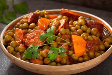 Geleneksel bir Romanya kasesinde havuç ve domuz sosisi ile bezelye güveci