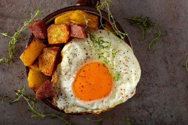 Patates kızartmalı yumurta ve kırsal bir tavada kızarmış salam.