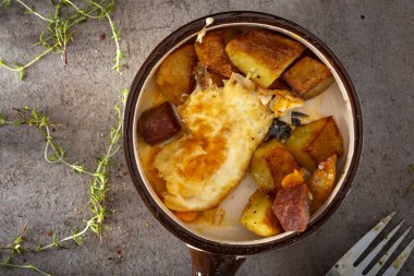 Patates kızartmalı yumurta ve otlu bir tavadan kızarmış salam yemek.