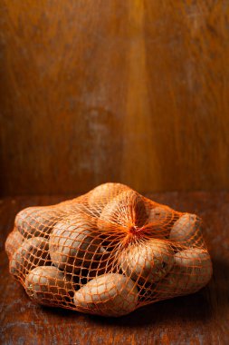 Ahşap arka planda bir çuval çiğ patates.