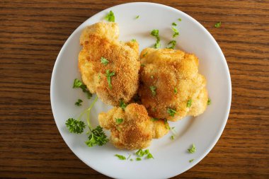 Karnabahar, yanında doğranmış maydanozla tabakta kızarır.