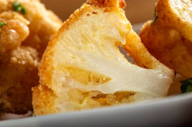 Karnabahar, yanında doğranmış maydanozla tabakta kızarır. Yakın görüş.