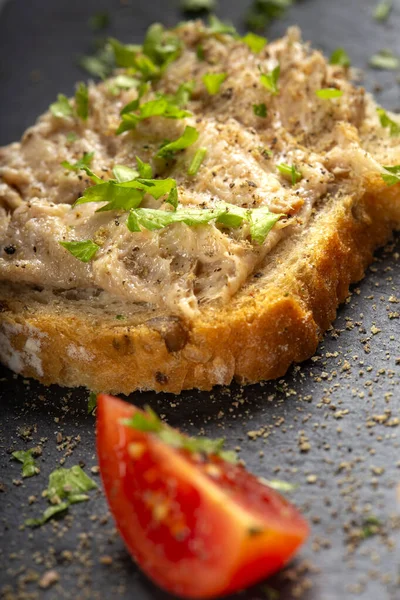 Koyu bir levhada domuz etli ekmek ve karabiber ezmesi.