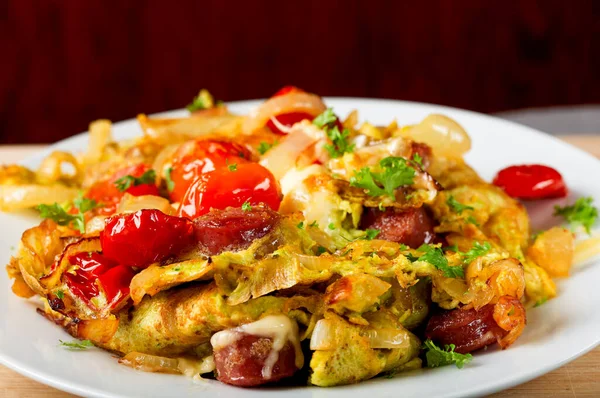 Soğanlı taze omlet, domuz sosisi, domates ve peynir tabakta.
