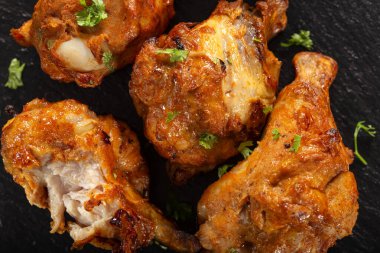 Roasted chicken drumstick on dark slate - top view